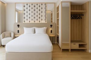 バレンシアにあるPetit Palace Plaza de la Reinaの白いベッドと椅子のある寝室