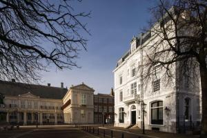 een wit gebouw aan de kant van een straat bij ADAM & EVE Paleisstraat in Den Haag
