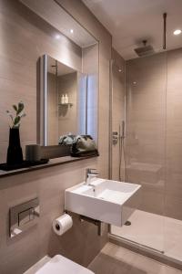 a bathroom with a sink and a shower and a mirror at The Hobson Cambridge by Adina in Cambridge