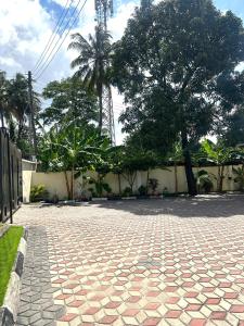 a brick courtyard with trees and a building at Stay with Recxy 1 in Dar es Salaam