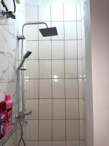 a white tiled bathroom with a shower with a solar light at Stay with Recxy 1 in Dar es Salaam