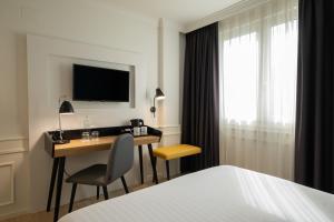 a hotel room with a desk with a television and a bed at Dorma Sardinero in Santander