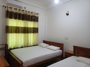 a bedroom with two beds and a yellow curtain at Elephant View Hotel in Damana