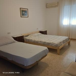 two twin beds in a room with a window at Finca el abuelo in Carmona