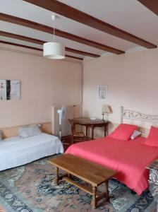 a bedroom with two beds and a wooden table at Gîte La Bonnetière in Ballan-Miré