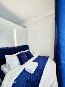 a bed in a room with blue and white pillows at Affordable Condotel near Sm Megamall with Fast WiFi in Sampong