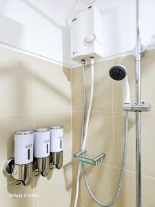 a shower in a bathroom with two cups at Affordable Condotel near Sm Megamall with Fast WiFi in Sampong