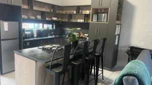 a kitchen with black cabinets and a counter with stools at MiCasa 62 in Potchefstroom