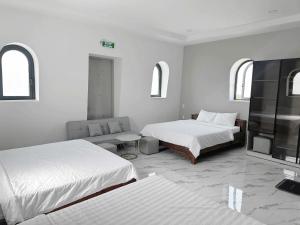 a white room with two beds and a couch at Anh Thư Hotel in Ấp Bình Hưng