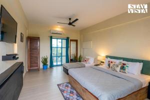 Un dormitorio con una cama grande y un televisor. en StayVista at Thalassa Near The Beach, en Alibaug