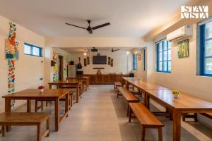 un comedor con mesas y bancos de madera en StayVista at Thalassa Near The Beach, en Alibaug