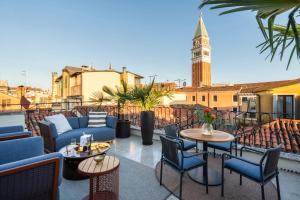 a patio with chairs and tables and a clock tower at Palazzo Rota Luxury Apartments in Venice