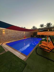 a swimming pool with two chairs and a umbrella at Al Zain Chalet - Private Pool in Al Kafrayn