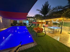 a swimming pool in a house with a table and a ping at Al Zain Chalet - Private Pool in Al Kafrayn +4 photos