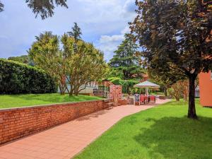 a brick wall next to a park with a table and umbrella at Cappuccini Friends in Peschiera del Garda