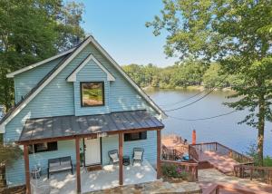 a blue house with a table and chairs in front of a lake at Lakefront Escape with Sauna Hot Tub BBQ & Games in Norris Lake Shores +43 photos