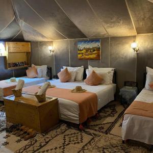 a bedroom with two beds in a tent at Aurum Dunes Luxury Camp in Merzouga +65 photos