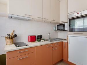 a small kitchen with orange cabinets and a sink at En Centre ville Gare et commerces in Vincennes