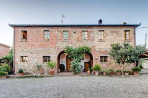 un gran edificio de ladrillo con plantas delante en Agriturismo Il poggiarello, en Foiano della Chiana