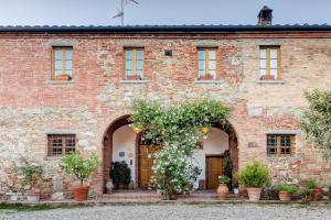 un antiguo edificio de ladrillo con una entrada con plantas floridas en Agriturismo Il poggiarello, en Foiano della Chiana