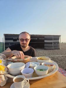 a man sitting at a table with a plate of food at Jabreen Castle Camp in Naţţālah