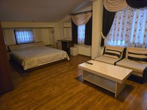 a bedroom with a bed and a couch and windows at Стаи за гости Дани in Zlatograd