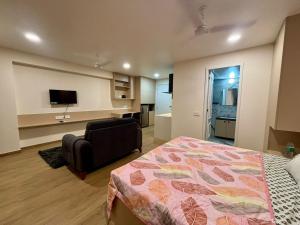 a bedroom with a bed and a couch and a television at Aura Living in Pune
