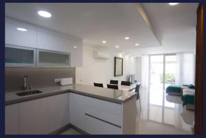 a white kitchen with a sink and a couch at Relax Blue Marlin Pasito Blanco in Pasito Blanco