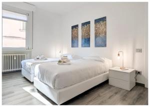 ein weißes Schlafzimmer mit 2 Betten und einer Lampe in der Unterkunft Flats4rent Verona Elegance Luxury Apartment in Verona