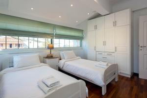 two beds in a room with white cabinets at Kassiopi Home in Kassiopi +21 photos