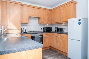 エディンバラにあるElegant 3BR Home, City Centre and Free Parkingの木製のキャビネットと白い冷蔵庫を備えたキッチン +20枚の写真