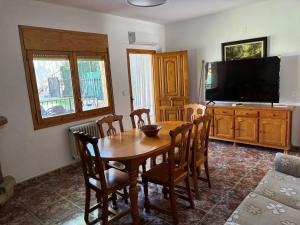 a dining room with a wooden table and a television at Residencial Los Robles in Arroyo Frio
