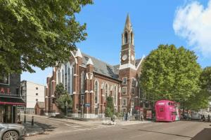 a pink bus parked in front of a brick building with a clock tower at 2 Bed Flat in Bethnal Green in Moffat