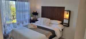 a bedroom with a bed with white sheets and a window at Dinky's Place in Herolds Bay