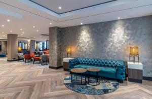 a lobby with a blue couch and tables and chairs at NYX Hotel Erfurt by Leonardo Hotels in Erfurt