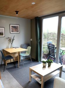Una sala de estar con una mesa y sillas y una ventana. en Logeerruimte Bij Ton, en Beilen