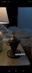 a tea pot on a table next to a bed at شقة البشائر in Al Khawḑ +4 photos