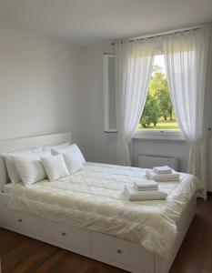 a white bed with white pillows and a window at Tenuta Vinci in Capannori