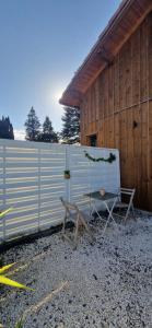 Un banco y una silla delante de una valla en Pinéa Lodge - Chalet Authentique en Pin des Landes, en Saint-Yaguen