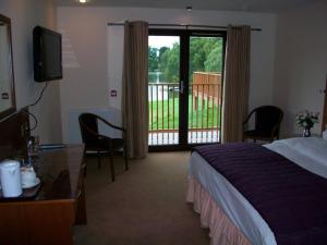 a hotel room with a bed and a balcony at The Lodge on the Loch in Aboyne