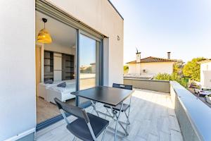 einen Tisch und Stühle auf dem Balkon eines Hauses in der Unterkunft La maison Barthe design 4ch clim parking privé in Toulouse