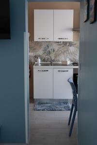 a kitchen with white cabinets and a table and a chair at La Terrazza di Porticello in Porticello +13 photos