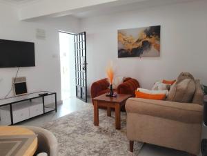 a living room with a couch and a tv at Erwin Holiday Homes in Diani Beach