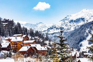 a town covered in snow with mountains in the background at Alba Lodge, 2 min de la télécabine, vue montagnes in Brides-les-Bains