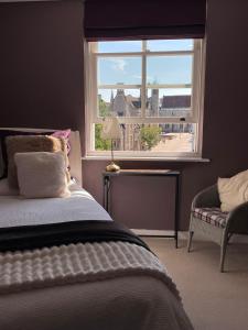a bedroom with a bed and a window and a chair at Luxury City Centre Apartment, Winchester in Winchester