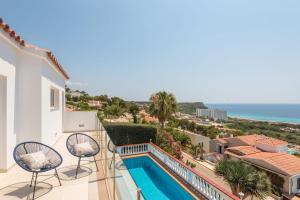 a balcony with two chairs and a swimming pool at Villa del Mar by Menorca Vacations in Son Bou