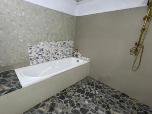 bagno con vasca e pavimento piastrellato. di Banchasramanora resort a Ban Nua