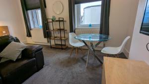 Una sala de estar con una mesa de cristal y sillas. en Captivating 1-Bed apartment Merthyr Tydfil -, en Merthyr Tydfil