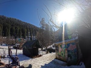 Un sol brillando sobre una tienda de campaña en la nieve en Cliff Seek, en Kalgha
