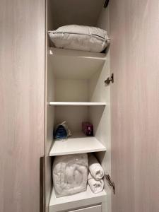 a closet with white shelves with towels and a pillow at HARF310 Modern Studio w Balcony at Yas Island in Abu Dhabi